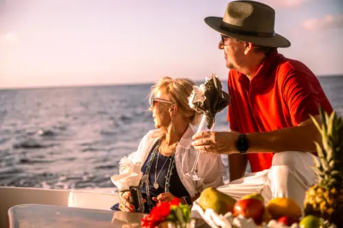 Couple on a luxury yacht at sunset, gazing out to sea.